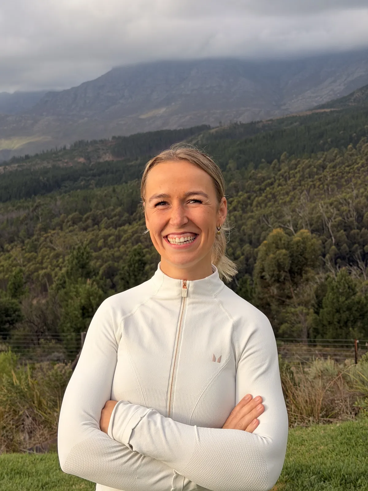 Jana Schlemm mit verschränkten Armen vor einer Berglandschaft, lächelnd